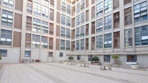 Un bâtiment moderne doté d’une cour intérieure, avec un espace central ouvert agrémenté de bancs et de plantes en pot.