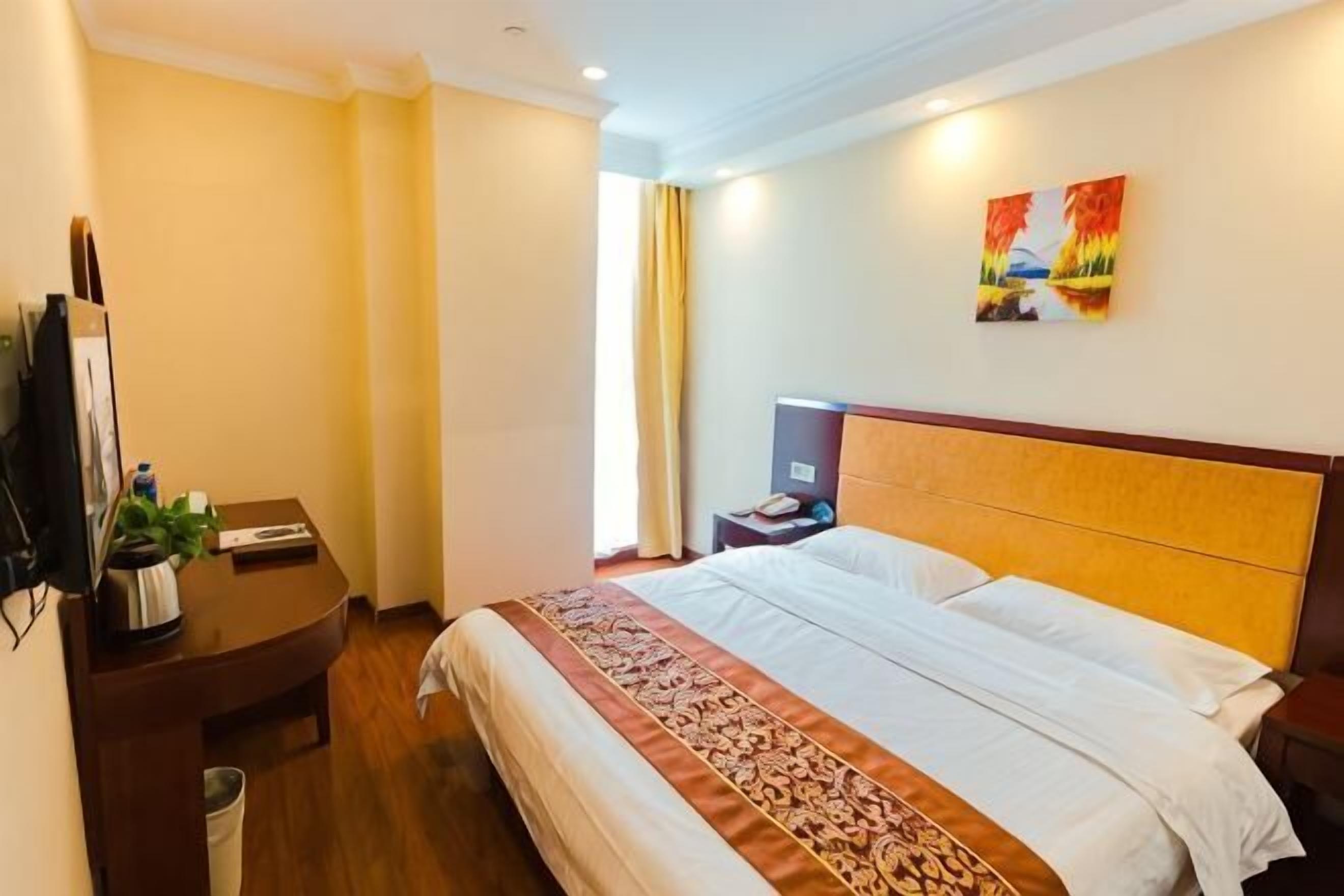 A hotel room with a bed, bedside table, nightstand, and a TV.