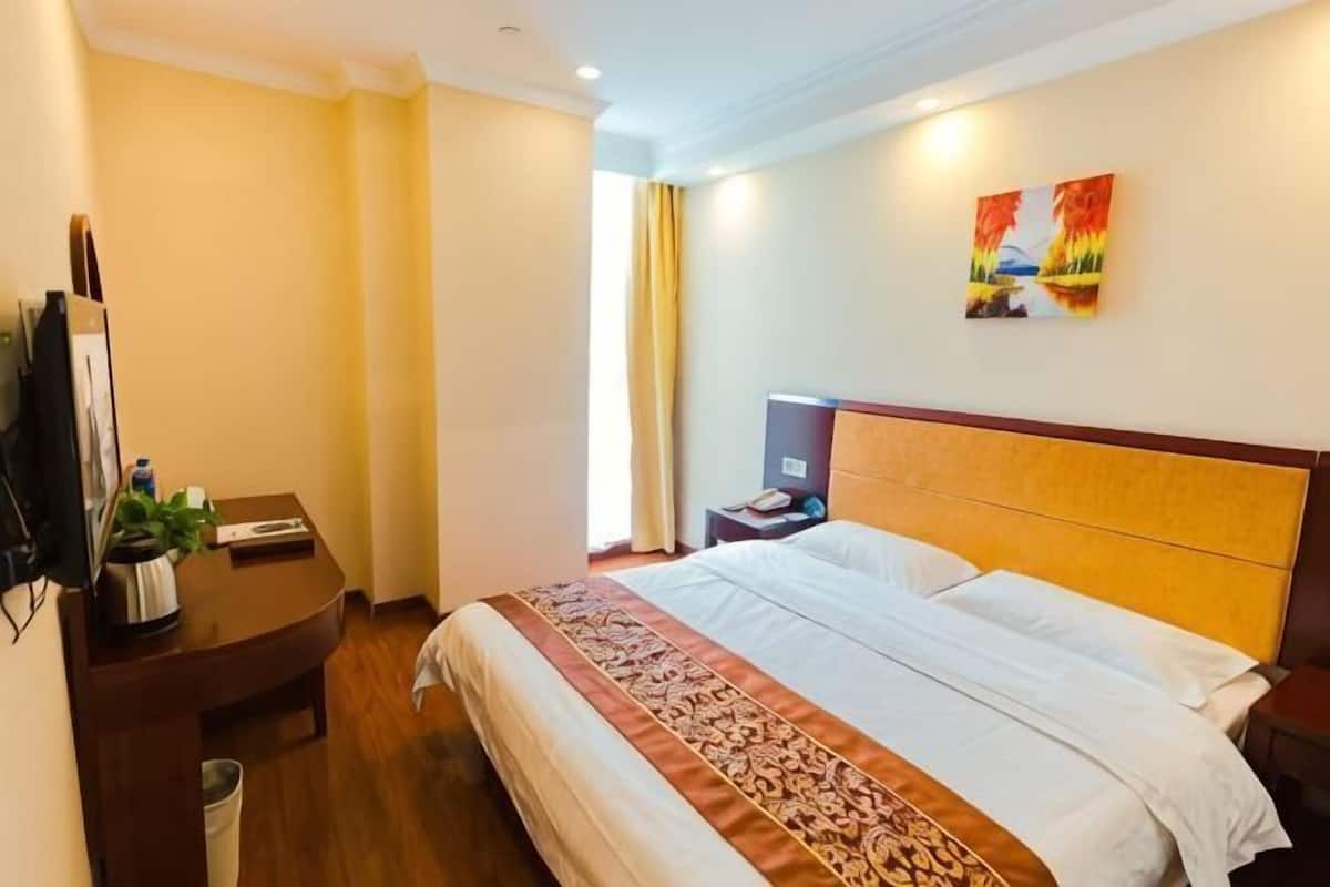 A hotel room with a bed, bedside table, nightstand, and a TV.