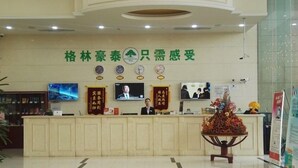 A hotel reception area with a reception desk, a television screen, and a decorative plant. - GreenTreeInn JiaDing F1Circuit FangTai HardwareMarket Hotel (Shanghai)