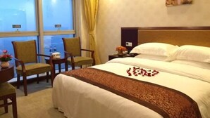 A hotel room with a large bed, a nightstand, two chairs, a window with curtains, and a painting on the wall. - GreenTreeInn JiaDing F1Circuit FangTai HardwareMarket Hotel (Shanghai)
