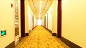 A hotel corridor with a patterned carpet, wooden doors, and a long hallway with a ceiling light fixture. - GreenTreeInn JiaDing F1Circuit FangTai HardwareMarket Hotel (Shanghai)