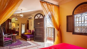A room with a bed, a chair, a small table, and a window with curtains. - Riad La Kahana (Marrakech)
