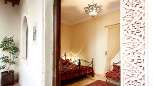 A bedroom with a bed, a potted plant, a patterned rug, and a decorative wall panel. - Riad La Kahana (Marrakech)