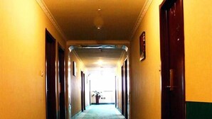 Un long couloir étroit, dont le sol est recouvert de moquette et où l’on trouve des portes de part et d’autre.