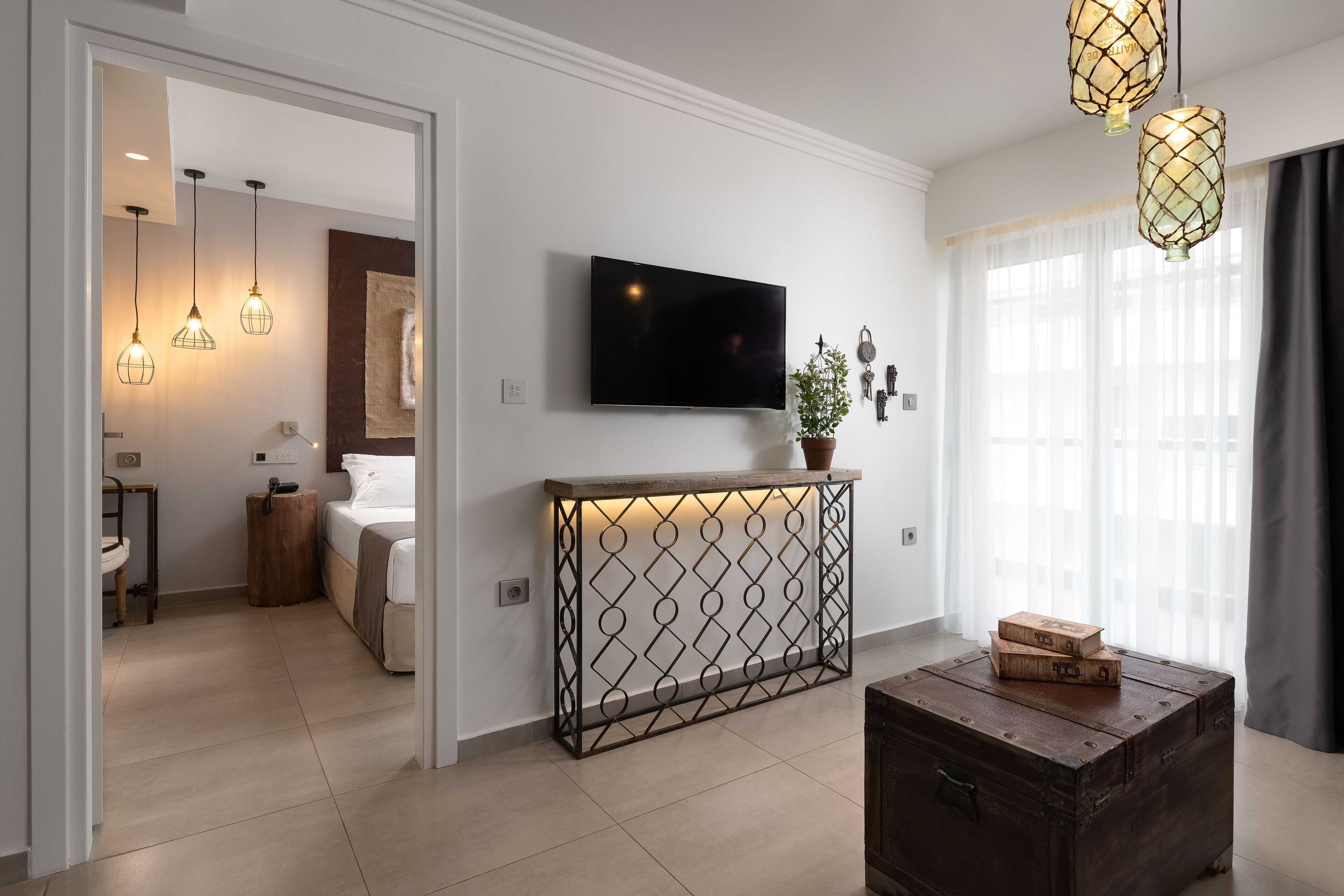 Een moderne woonkamer met een flatscreen televisie, een console tafel met een plant, en een vintage koffer.