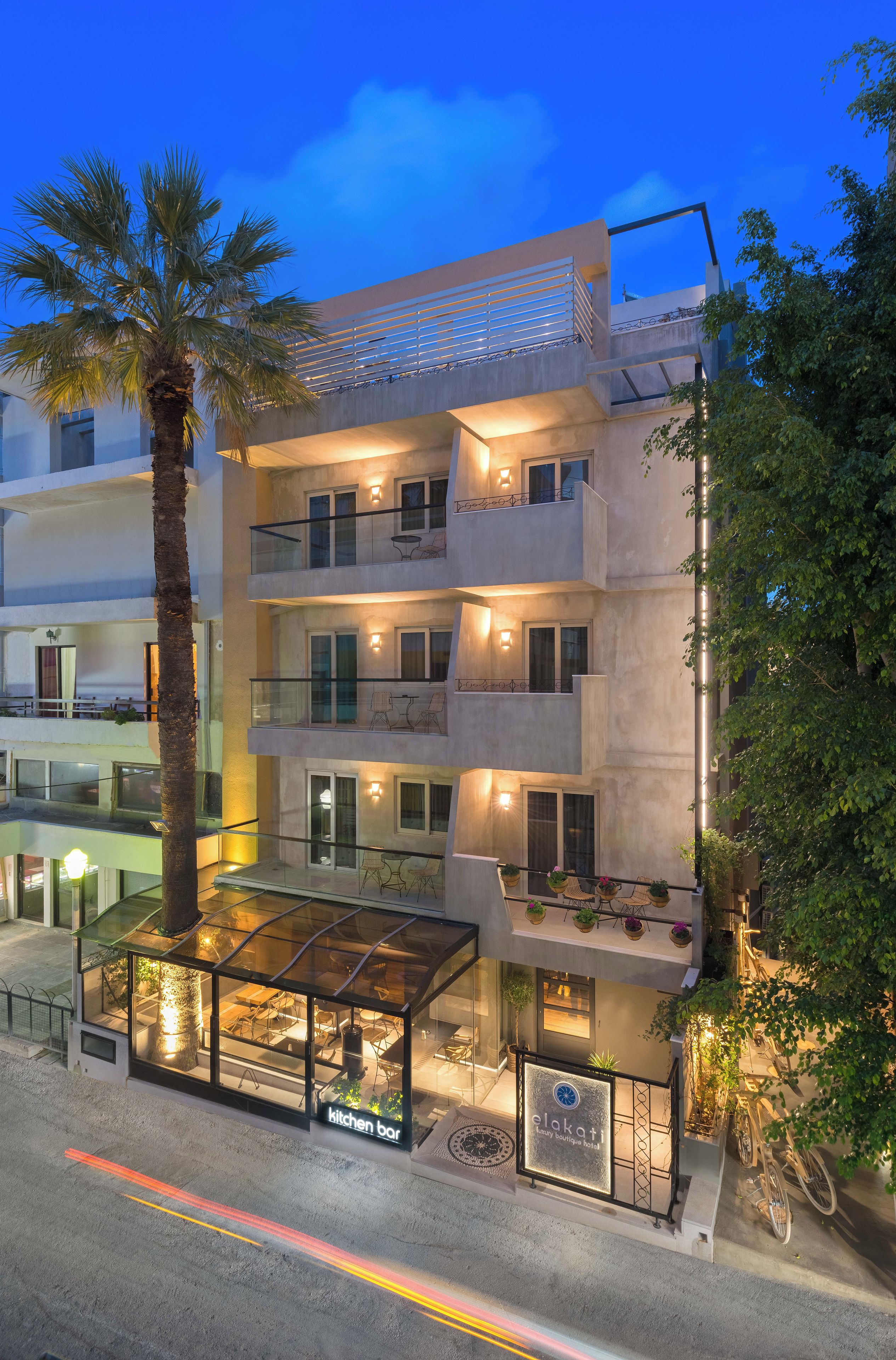 A multi-story hotel with balconies, outdoor seating, and a glass-enclosed area.