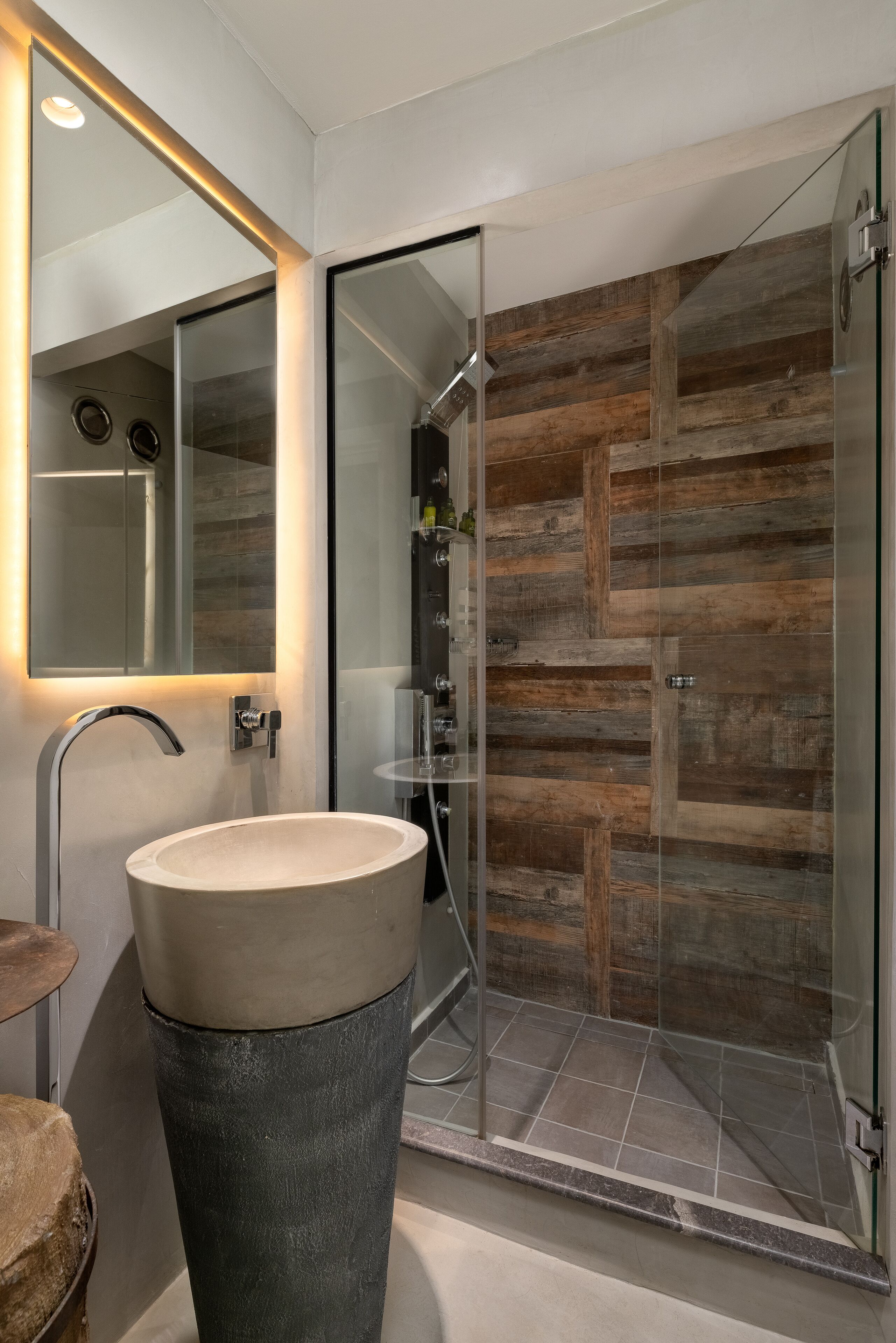 Ein modernes Badezimmer mit einem großen Waschbecken, einer Duschkabine aus Glas und einer Wand mit Holzverkleidung.