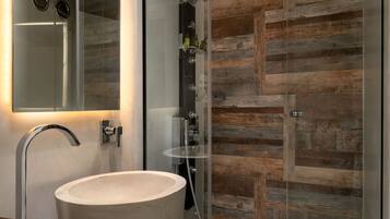 Ein modernes Badezimmer mit einem großen Waschbecken, einer Duschkabine aus Glas und einer Wand mit Holzverkleidung.