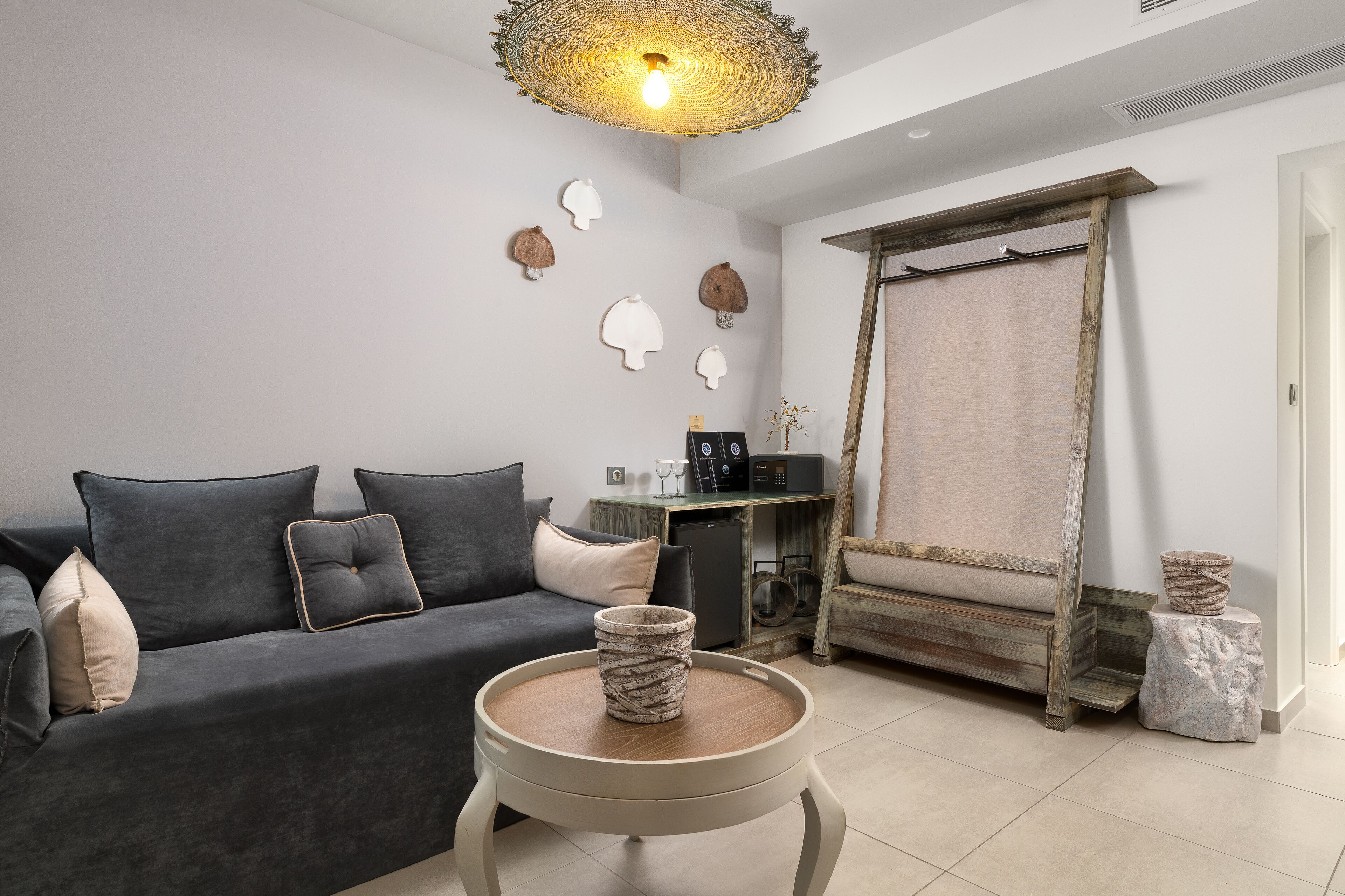 Un salon moderne avec un canapé gris foncé, une table basse ronde en bois et un luminaire original en fibres tressées.