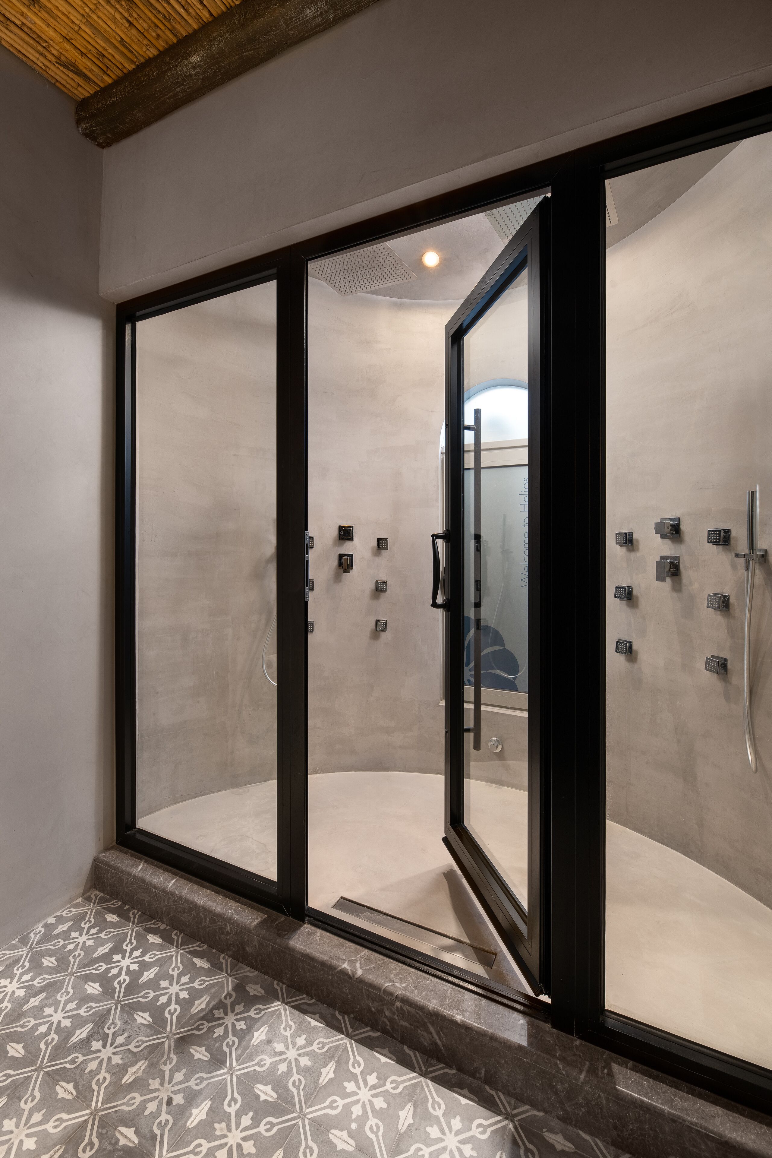 Un baño moderno con cabina de ducha de vidrio, suelo estampado y techo de madera.
