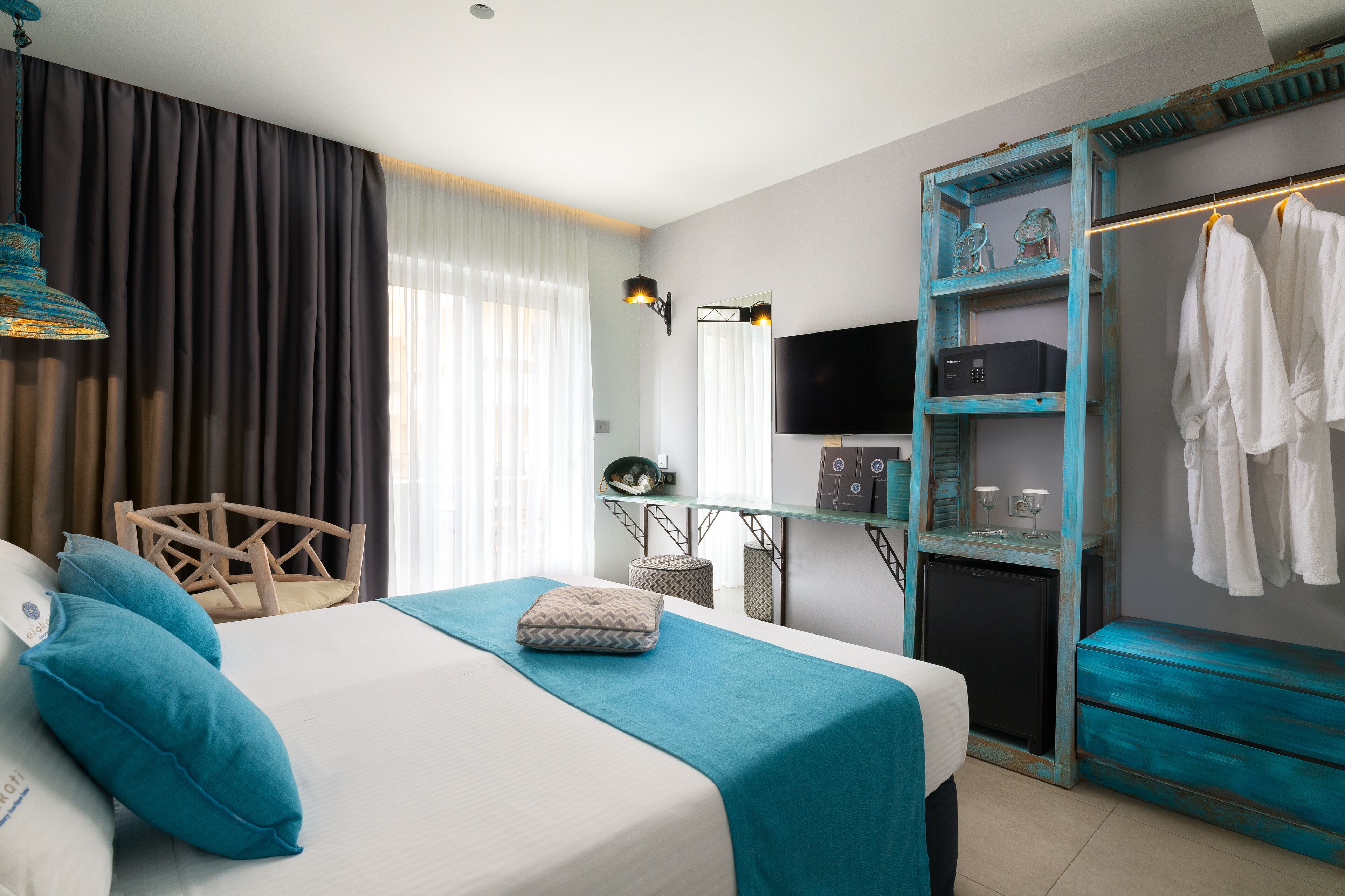 Een hotelkamer met een bed, een bureau, een televisie, een kledingkast en een spiegel.
