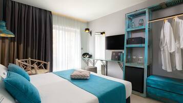 Een hotelkamer met een bed, een bureau, een televisie, een kledingkast en een spiegel.