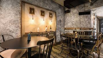 A rustic interior with a round table, chairs, and a bar area.