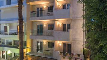 A multi-story hotel with balconies, outdoor seating, and a glass-enclosed area.