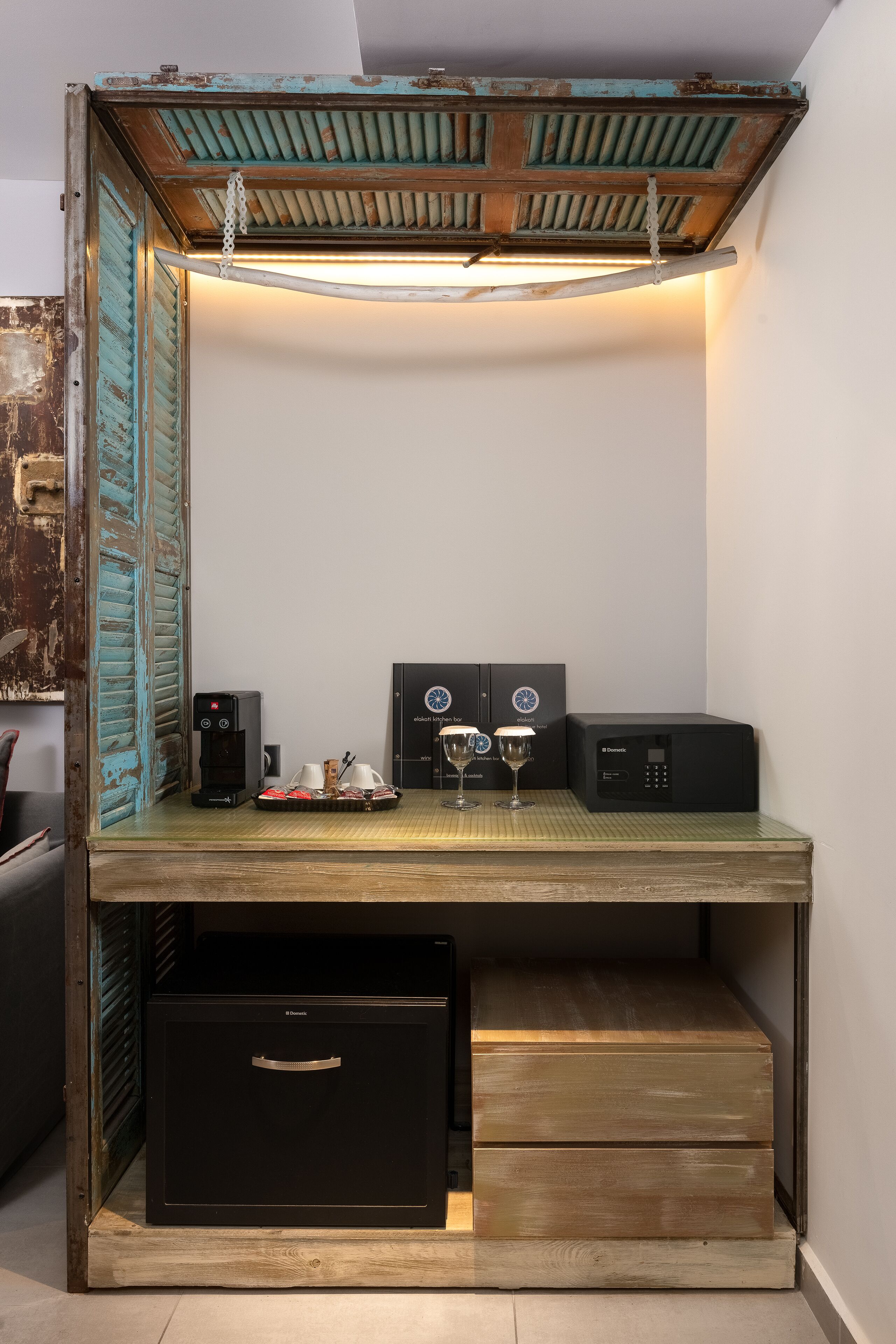 A compact workspace with a wooden desk, two black coffee machines, and two wine glasses.