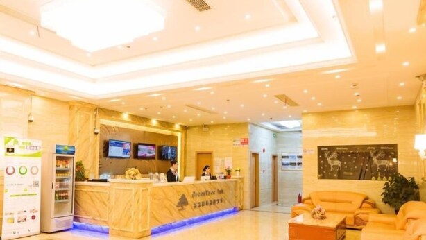Un hall de hotel con una recepción, zona de estar y máquina expendedora.