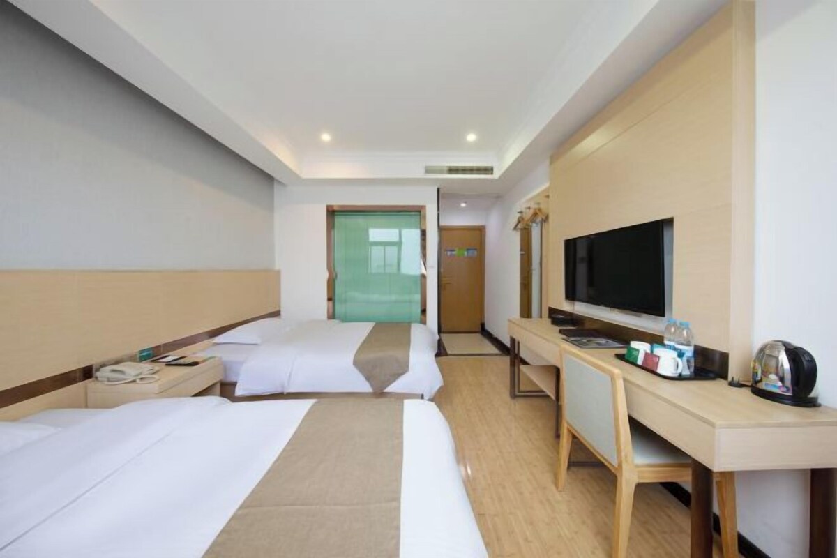 Una habitación de hotel con dos camas, un escritorio, un televisor y un minibar.