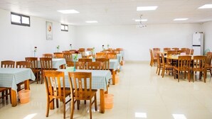 Un comedor amplio con varias mesas y sillas, dispuestas en forma de U.