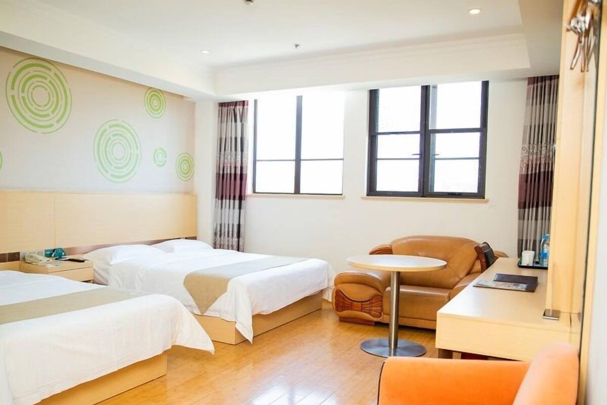 Een hotelkamer met twee bedden, een bank, een kleine tafel en een raam met gordijnen.