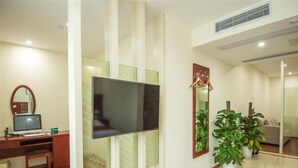A modern living room with a flat-screen TV, a wooden entertainment unit, a sofa, and potted plants. - Greentree Inn Suzhou Dongwu North Road Business Hotel (Suzhou)