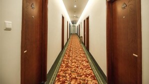 A hotel hallway with wooden doors, a carpeted floor, and a light fixture on the ceiling. - Greentree Inn Suzhou Dongwu North Road Business Hotel (Suzhou)