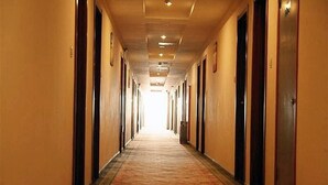 Un largo y estrecho pasillo de hotel con puertas a ambos lados y suelo alfombrado.
