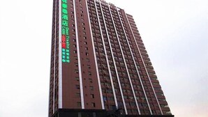 Un edificio alto y rectangular con un letrero vertical llamativo en su lateral.