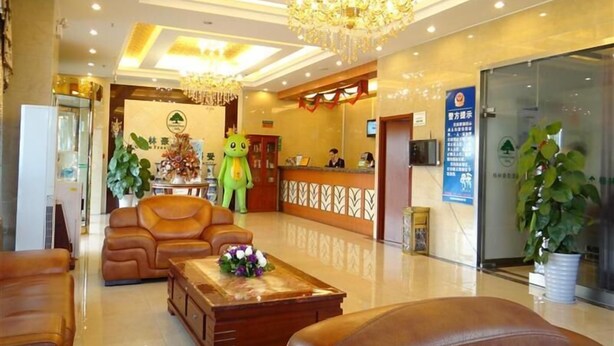 Un hall de hotel con sofás de cuero, un mostrador de recepción, una araña y una zona de recepción con recepcionista.