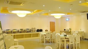A dining area with multiple tables and chairs, a counter with kitchen equipment, and a ceiling with recessed lighting. - GreenTree Inn Hefei Luyang District North Fuyang Road Luyang Industrial Park Express Hotel (Hefei)