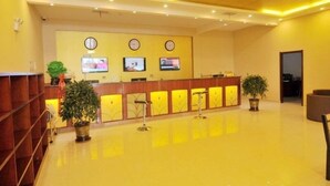 Zona de recepción de un hotel con mostrador, varios relojes y una araña.