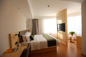 A hotel room with a bed, a desk, a TV, and a potted plant. - Greentree Inn Hebei Langfang Development Zone Conv (Langfang)