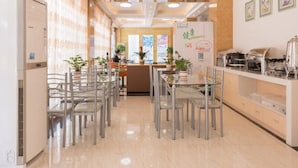 Un espace repas moderne avec une longue table, des chaises et un comptoir équipé de machines à café.