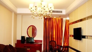 A hotel room with a wooden desk, a television mounted on the wall, a chandelier, and a large window with curtains. - GreenTree Inn Hefei Mingfa Square Express Hotel (Hefei)