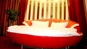 A circular bed with white bedding, red curtains, and a plant in a vase. - GreenTree Inn Hefei Mingfa Square Express Hotel (Hefei)