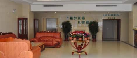 A lobby with a chandelier, sofas, a reception desk, and a sign for GreenTree Inn.