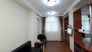 A hotel room with a black sofa, a small table, a TV, and a wooden wardrobe. - Greentree Inn Guangdong Shantou Changping Road Exp (Shantou)