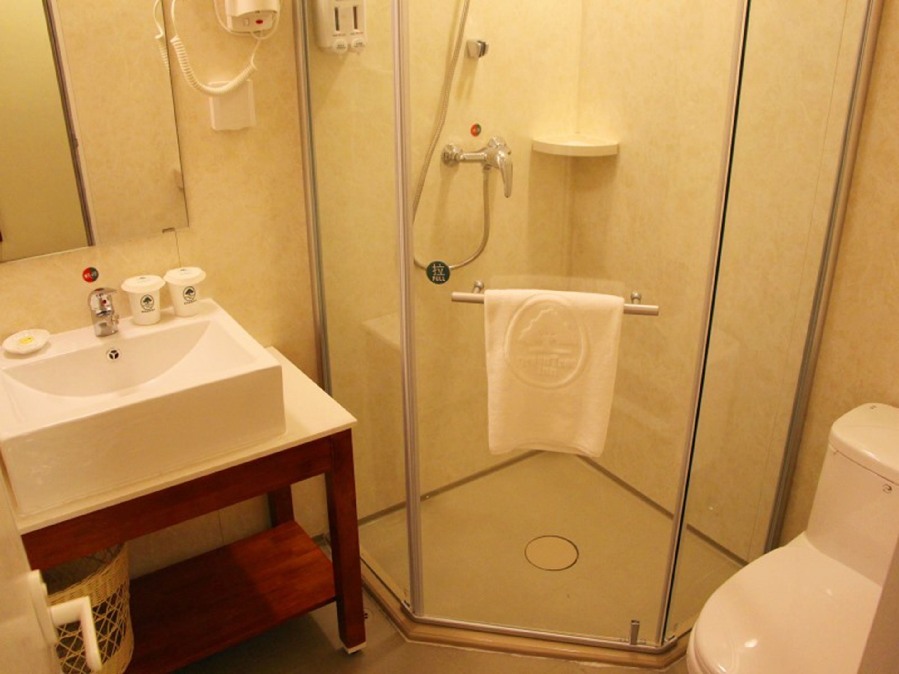Ein Badezimmer mit einer Duschkabine, einem Waschbecken mit Pflegeprodukten und einer Toilette.