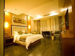 A hotel room with a large bed, a desk, and a chair.