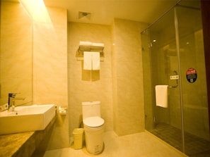 Un bany amb plat de dutxa de vidre, un lavabo i un vàter.