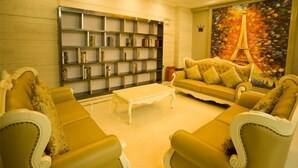 A living room with a sofa set, a bookshelf, and a painting of the Eiffel Tower.