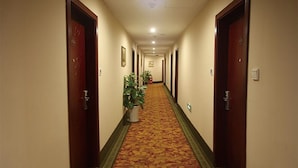 Ein Hotelkorridor mit Teppichböden, Holztüren und Blumentöpfen.