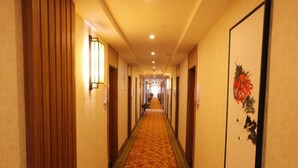 Un pasillo de hotel con suelo alfombrado, paneles de madera en las paredes y una obra de arte enmarcada a la derecha.