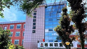 A hotel with a modern facade, featuring a prominent sign with Chinese characters.