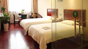 A hotel room with two beds, a desk, a chair, and a potted plant.