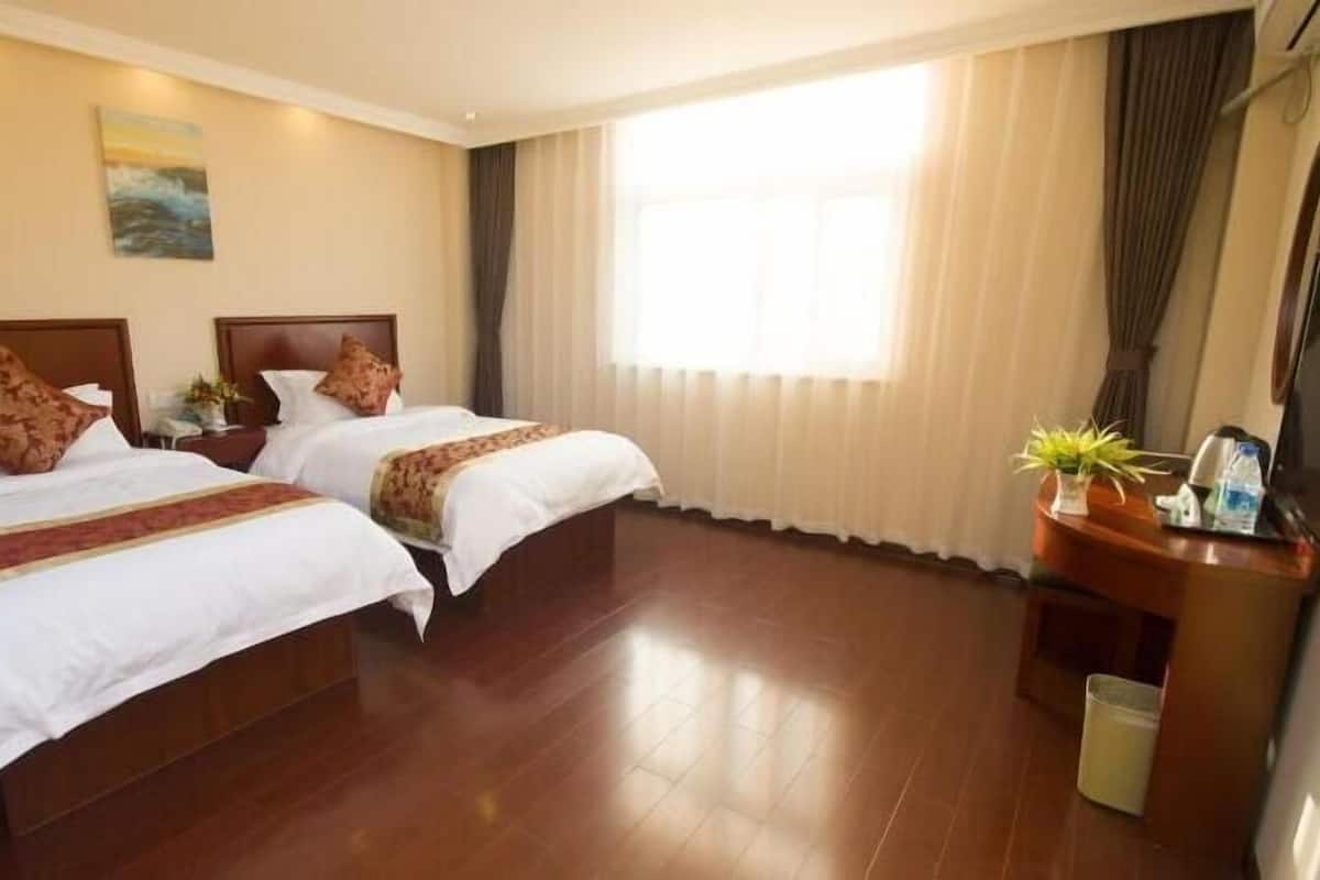 Une chambre d’hôtel avec deux lits, un bureau, une télévision et une fenêtre avec des rideaux.
