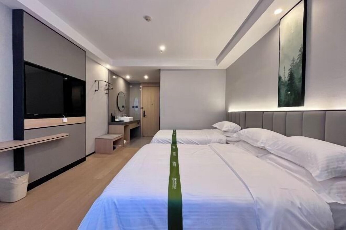 A modern hotel room with a large bed, a flat-screen TV, a mirror, and a painting on the wall.