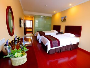 A hotel room with two beds, a large mirror, a small table with a plant, and a view of the hallway. - Greentree Inn Technology University Youth Square (Zhenjiang)