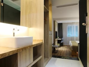 A modern hotel room with a large bathroom vanity, a desk, a chair, and a bed. - Vatica Fuzhou West Second Ring Road Xihu Park Hote (Fuzhou)