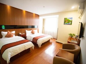 Habitación de hotel con dos camas, suelo de madera, un escritorio con silla, un cuadro en la pared y una ventana con cortinas.